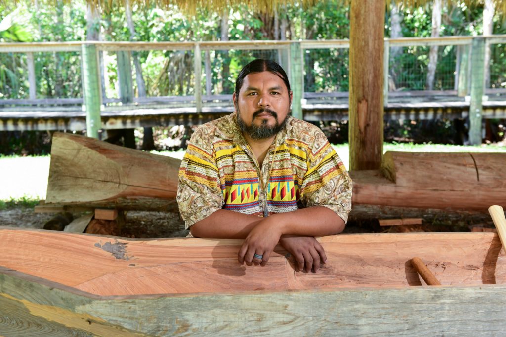 man leaning on a carved wooden canoe