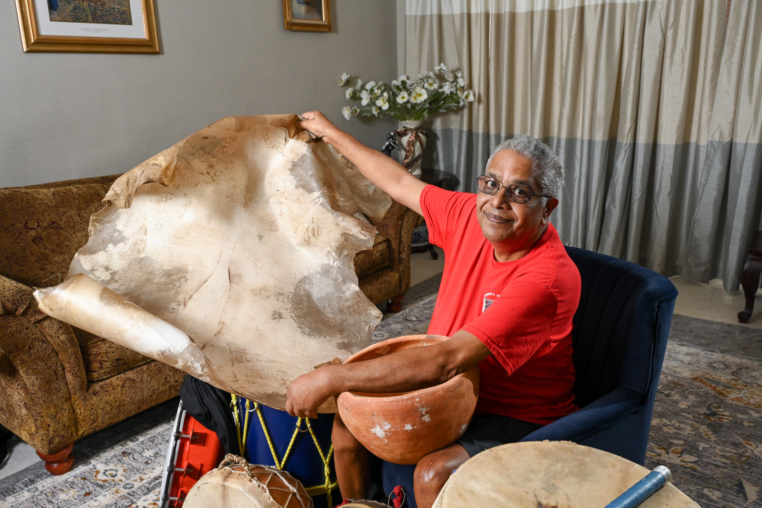Romeo Ragbir holds open a large piece of goat skin with various colors of brown and beige.