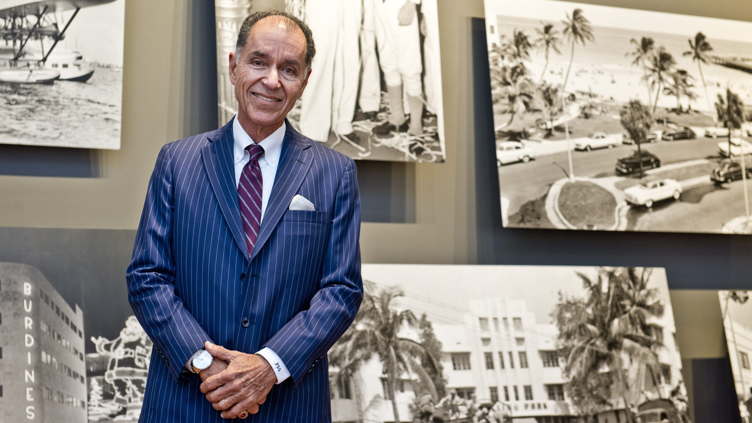 Dr. Paul George in a suit standing in front of archival images.