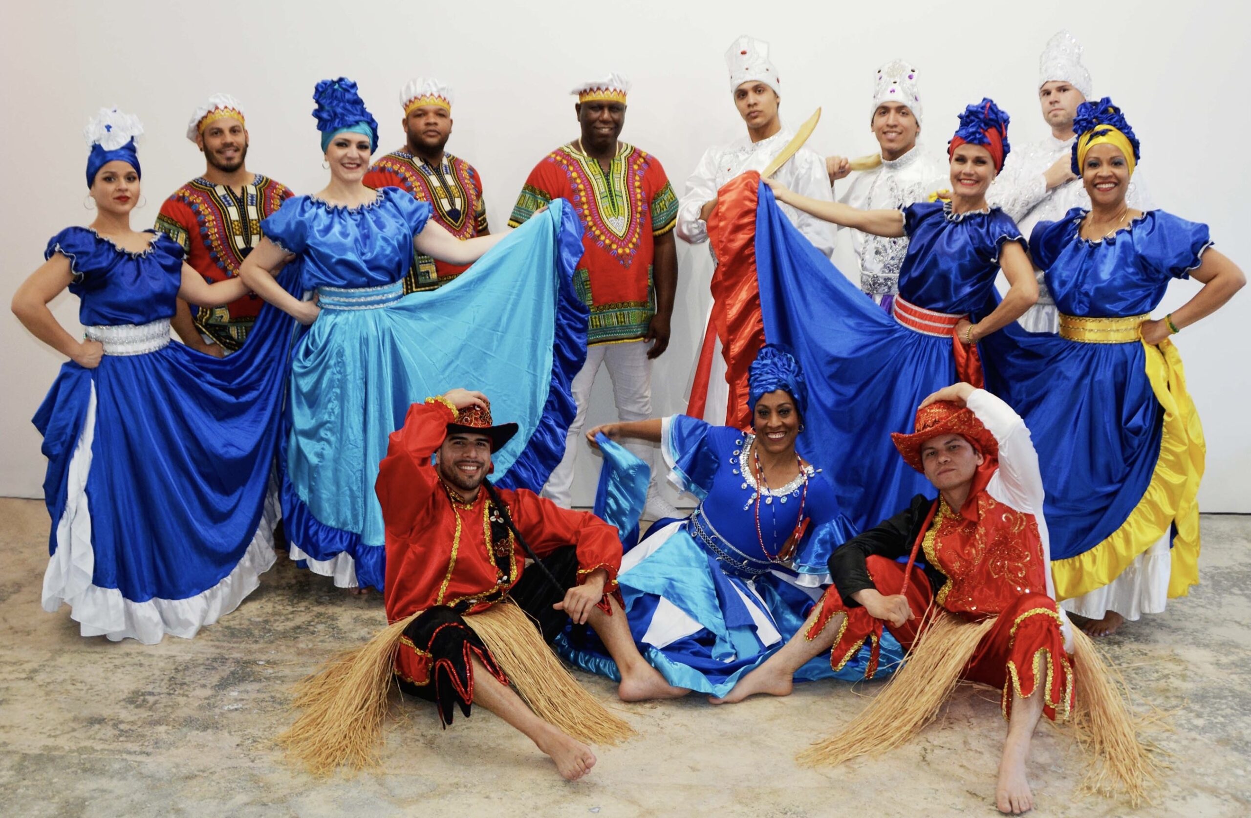 Dance ensemble of men and women pose in different styles of dance costumes.