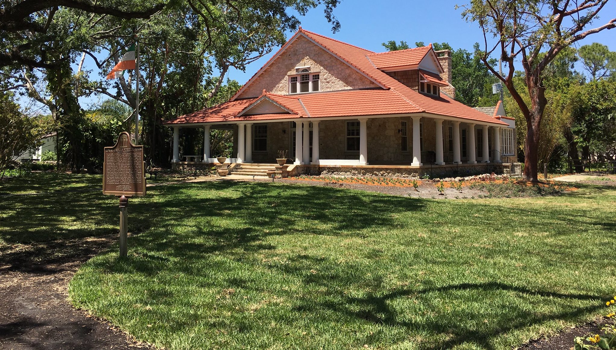 A brown house with triangular roof sits atop a grassy green lawn.