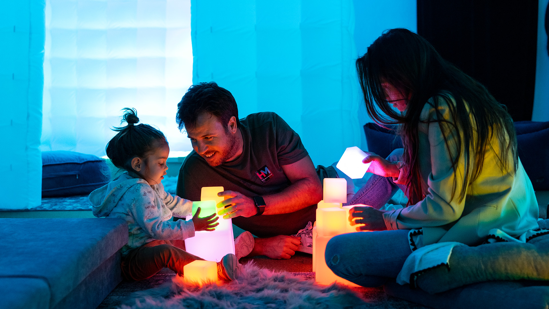 Family playing with lighted blocks in sensory room.