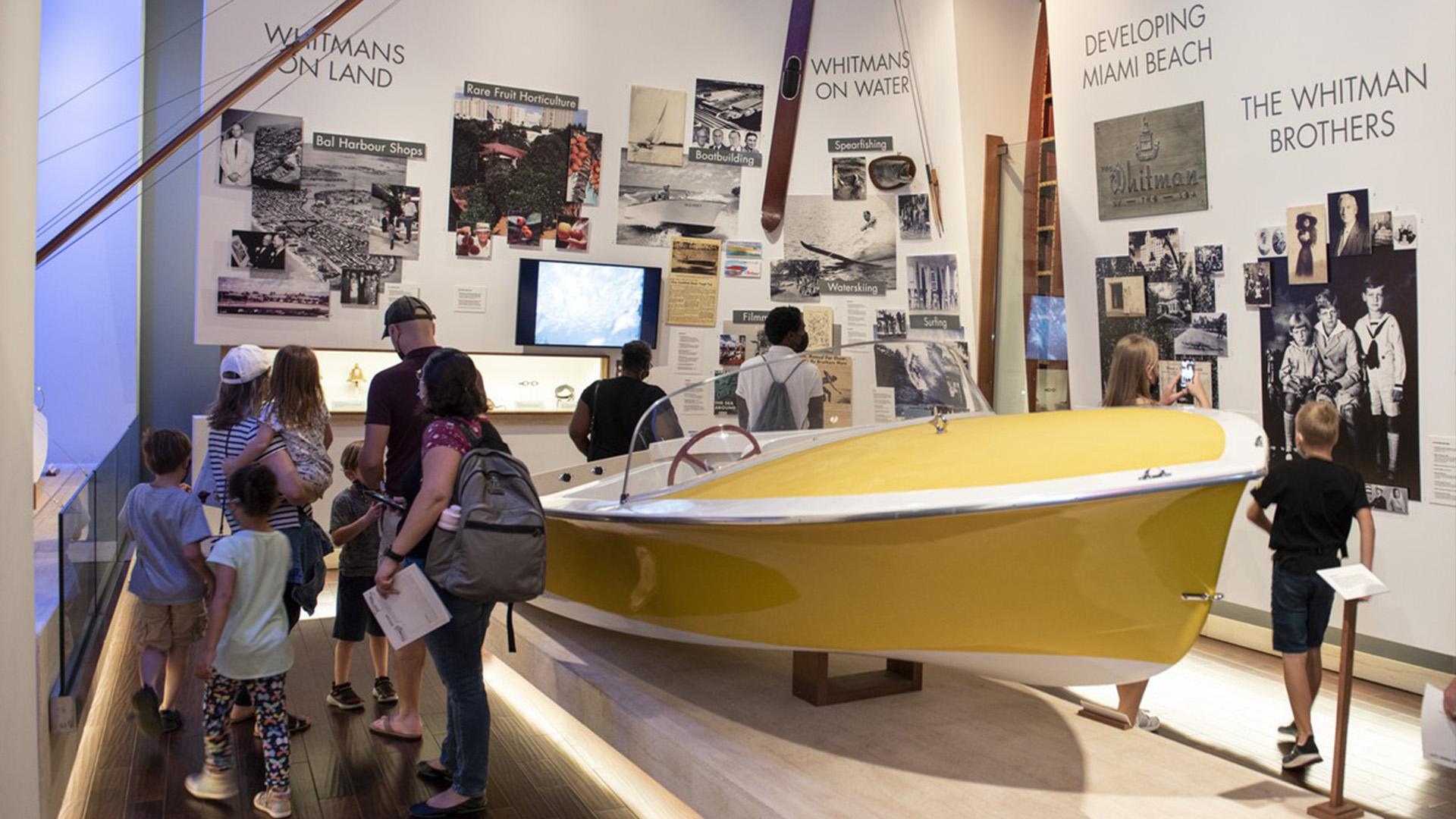 Families in the ,museum gallery looking boat.