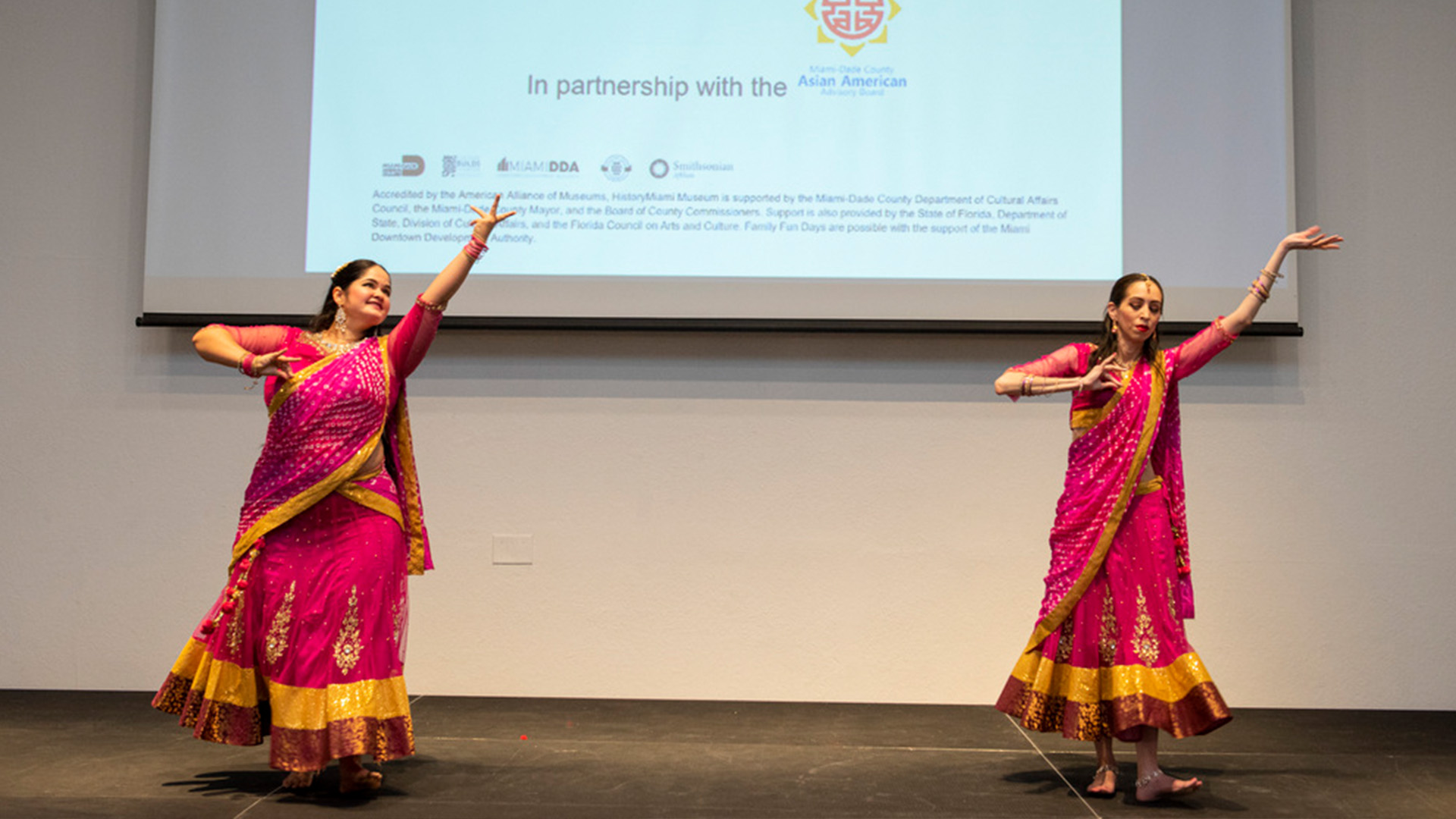 Dancers on a stage wearing bright pink dresses