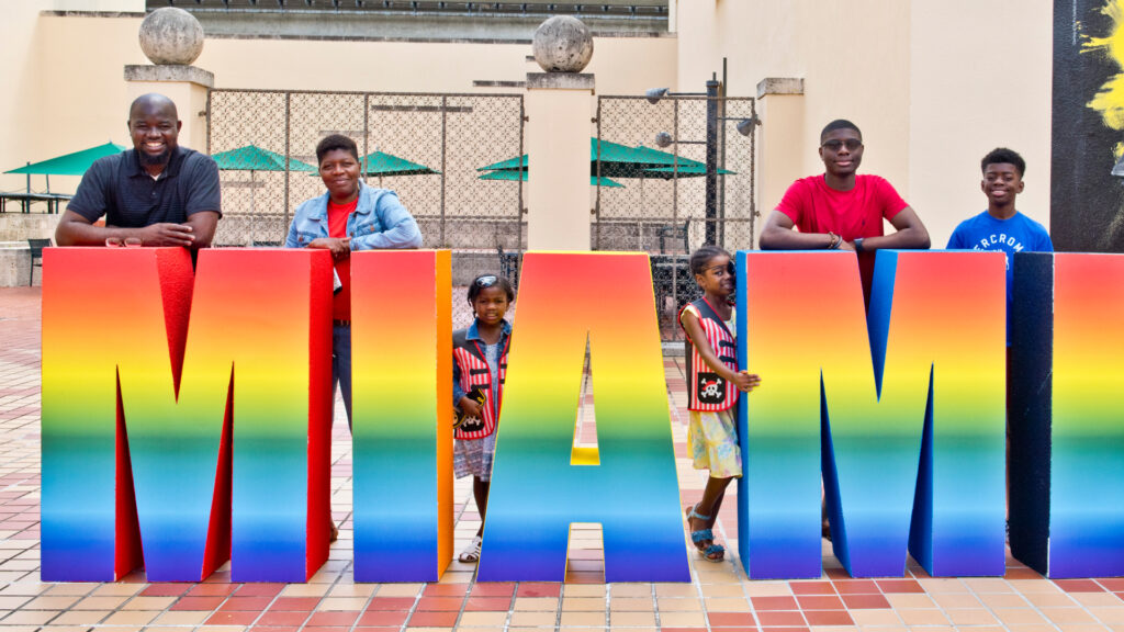 Family standing by Miami sign on the museum plaza.